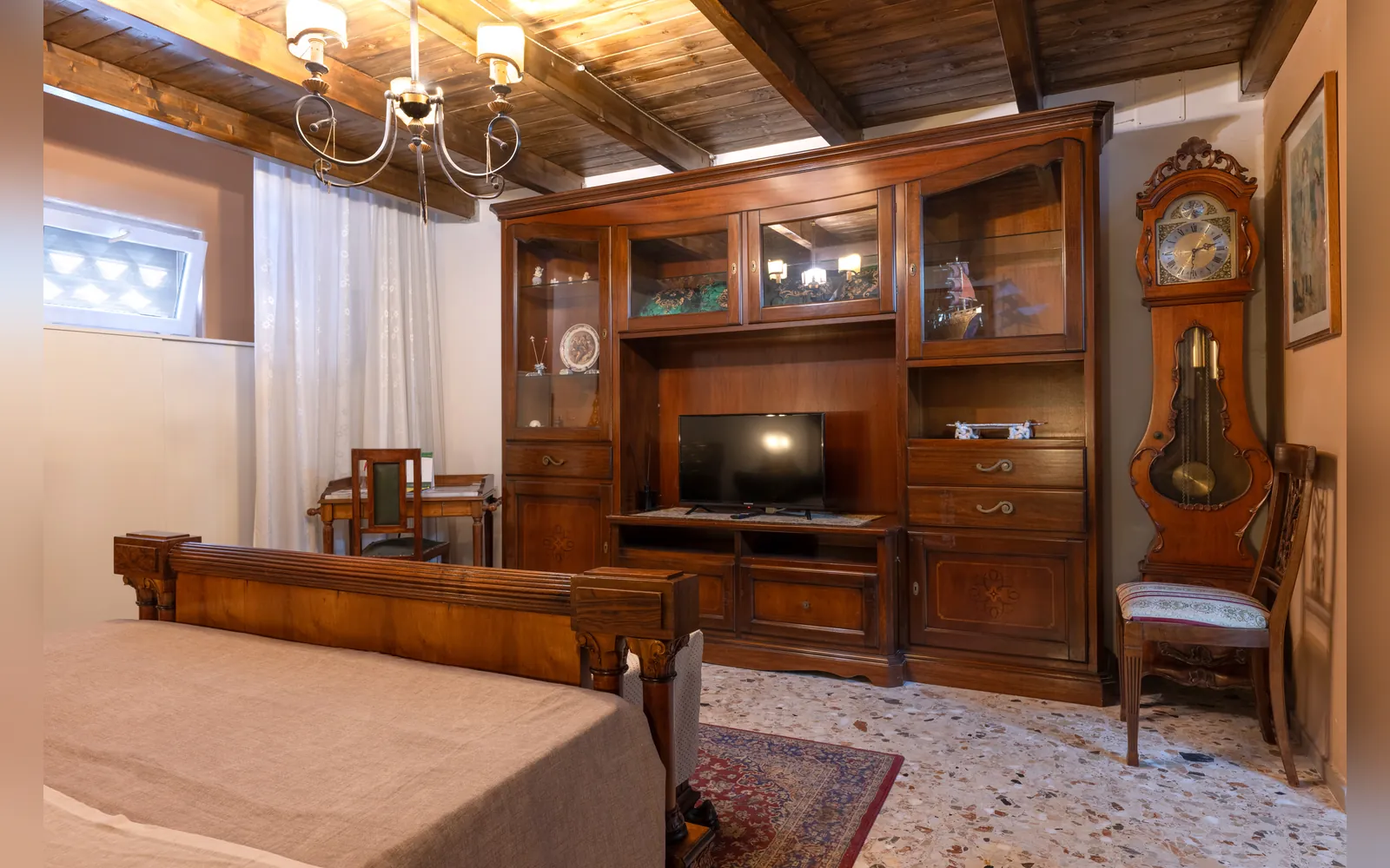 Appartamento MA.GI.A, ambiente con vetrina in legno, TV e orologio a pendolo