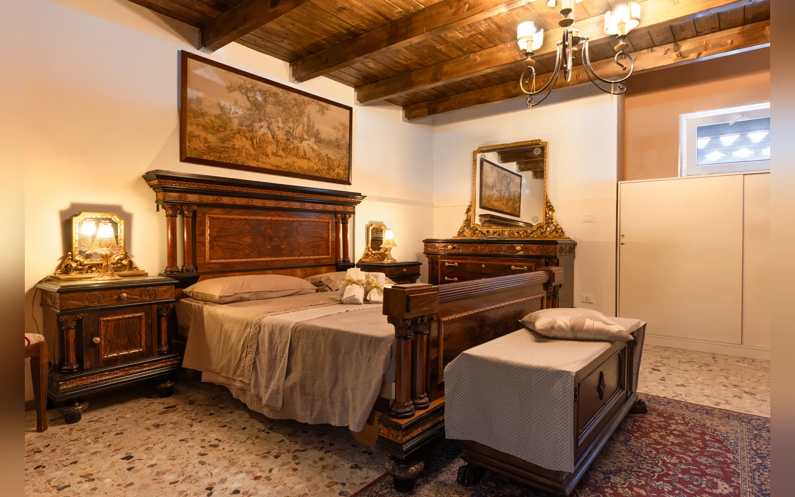 Appartamento MA.GI.A, camera matrimoniale con letto in legno intarsiato e arazzo