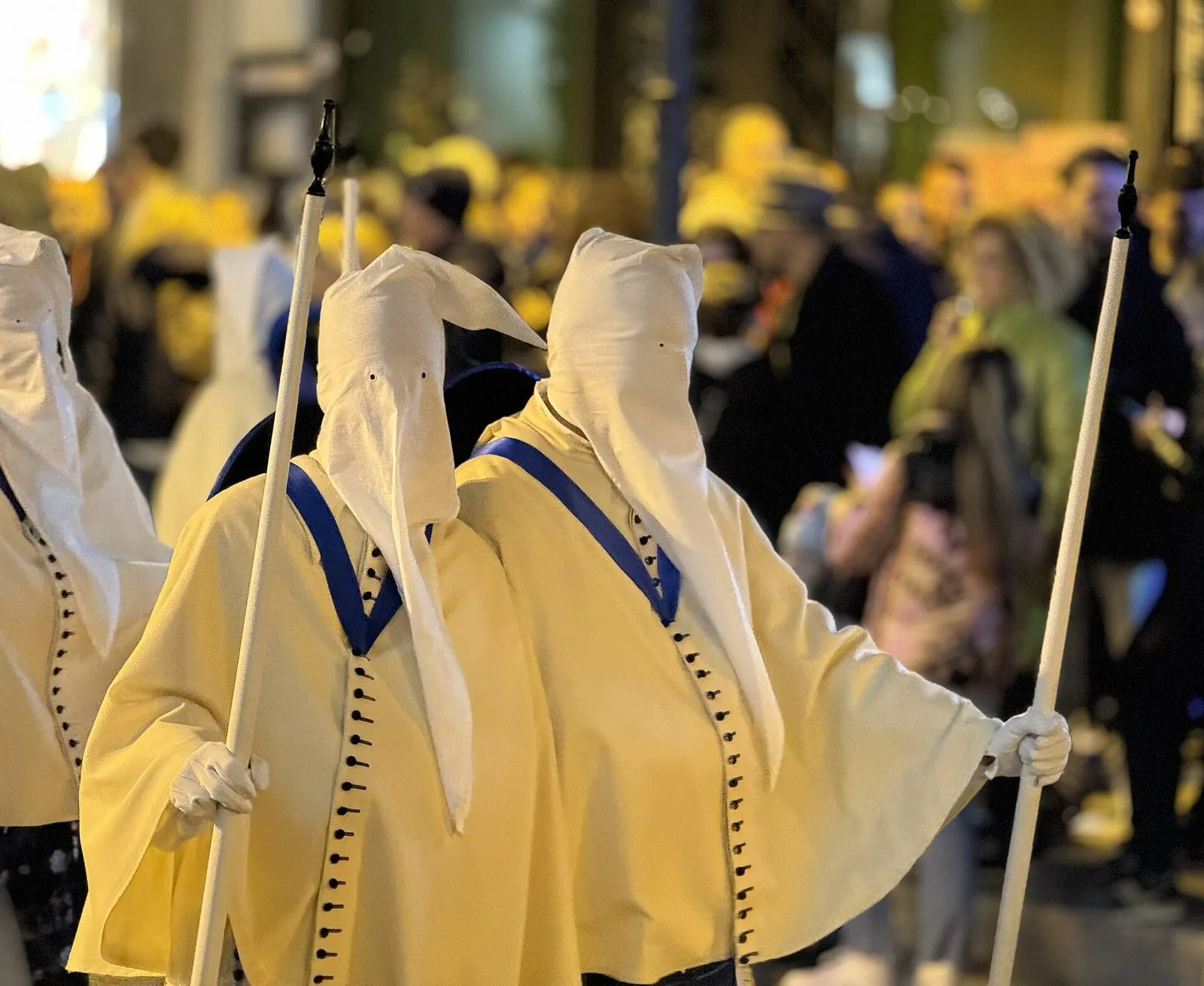 Coppia di Perdoni della Confraternita del Carmine, incappucciati con abito chiaro, guanti bianchi e bordone, durante la Settimana Santa a Taranto
